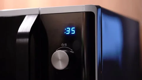 Man's hand twists microwave timer button, counts back 動画素材 231036719