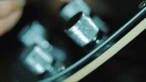 Man's hand twists volume control on polished electric guitar deck with knobs and 스톡 동영상 75778003