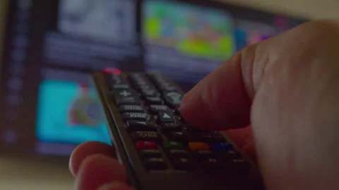 A man's hand uses a remote control to change the content on a tv. Stock Footage 335647996