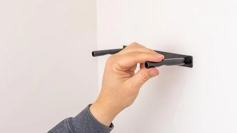 Mans hand using black marker to mark line on white wall above black shelf 写真素材