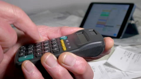 A man's hand using a calculator above many store / shopping receipts. Video stock 167280876