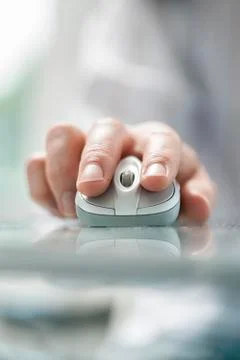 Man's hand using cordless mouse on glass table Stock Photos