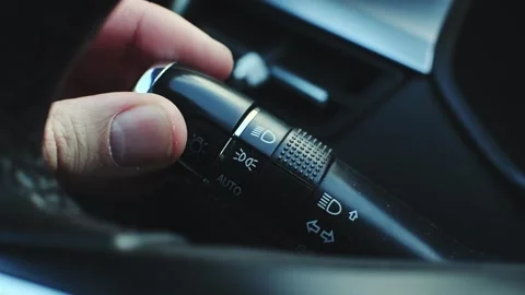 Man's hand, using a light switch knob, turns off the car's headlights. Stock Footage 287297105