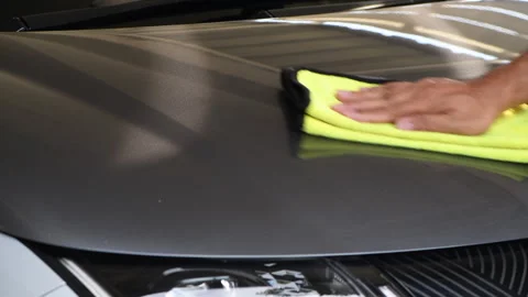 A man's hand is using a microfiber towel to clean the hood of an electric car. Stock Footage 322623592