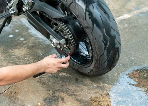 Man's hand using oil spray can to clean and protect motorbike chain.. Stock Photos