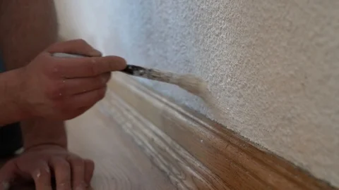 Man's hand using paintbrush with white paint on wall, interior Stock Footage 122012739