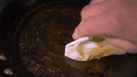 Man’s hand using paper towel to wipe fat from a frying pan. Stock-Footage 241586898