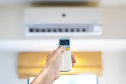 Man's hand using remote control open The air conditioner in his bedroom Foto stock