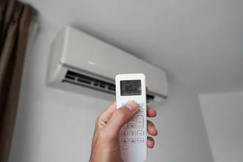 Man's hand using remote controler. Hand holding rc and adjusting temperature of Foto stock