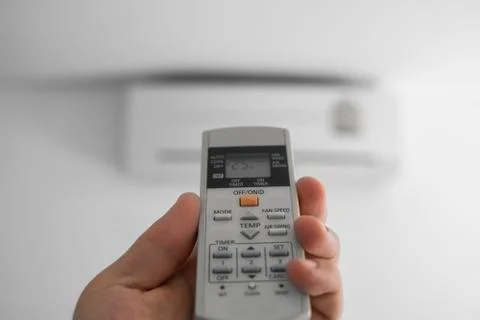 Man's hand using remote controler. Hand holding rc and adjusting temperature of Foto stock