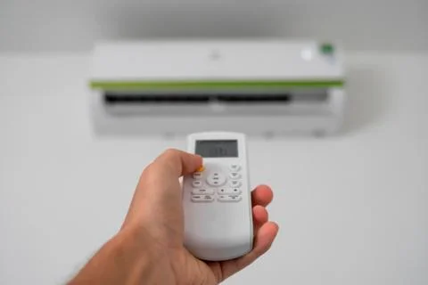 Man's hand using remote controler. Hand holding rc and adjusting temperature of Foto stock