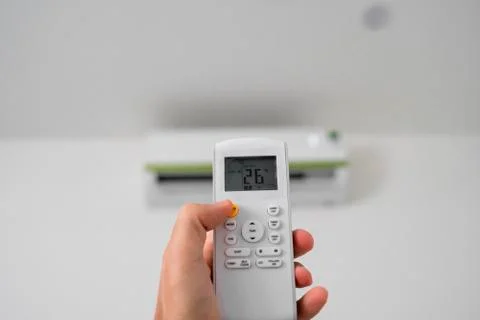 Man's hand using remote controler. Hand holding rc and adjusting temperature of Foto stock