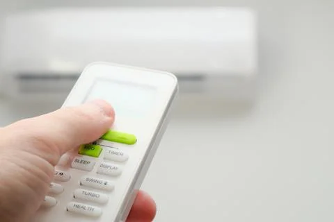 Man's hand using remote controler. Hand holding remote and adjusting temperat Foto stock