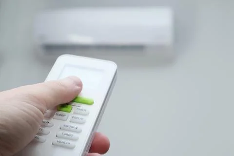 Man's hand using remote controler. Hand holding remote and adjusting temperat Foto stock
