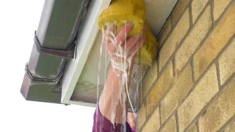 Man's hand using a soapy water sponge to clean house guttering woodwork. Video stock 157042555