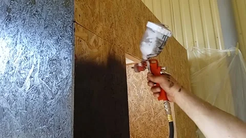 A man's hand using a spray gun evenly distributes paint on the surface of the Stock Footage 243763271