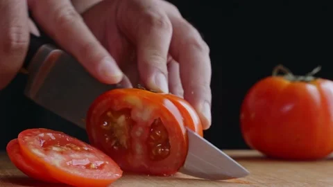 The man's hand was cutting tomatoes into small pieces on a cutting board. He is  Stock-Footage 145140219