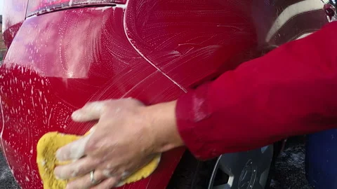 Man's hand washing a wet red car with a cloth sponge.  Close up shot Stock Footage 169083563