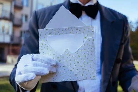 A man's hand in a white glove holds an open envelope with a place for text Foto stock