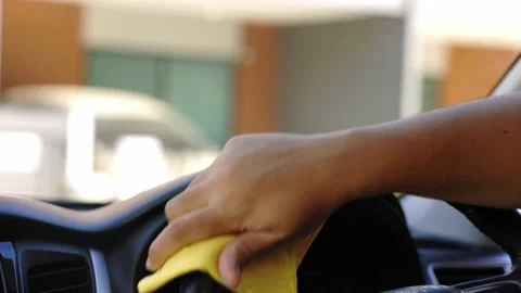 Man's hand wiped yellow microfiber cloth to clean the console and steering wheel Stock Footage 152747931