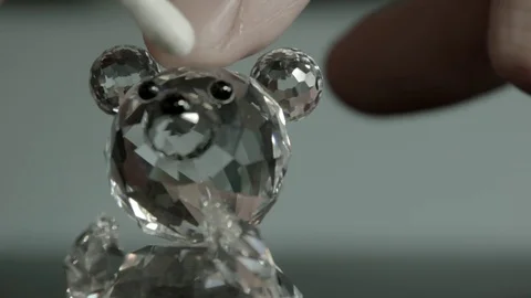Mans hand wipes face of small crystal bear using a cotton wool bud_Not B&amp;W Stock Footage 72165441