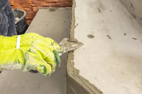 Man's hand in work gloves leveling the surface of a step before laying paving Stock Photos