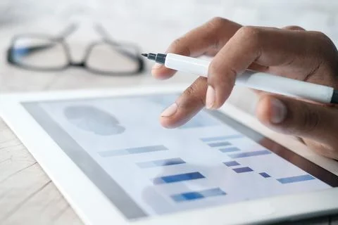 Man's hand working on digital tablet at office desk, using self created chart Stock Photos