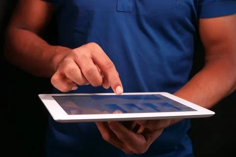 Man's hand working on digital tablet at office desk, using self created chart Stock Photos