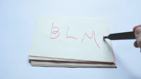 Man's hand writes abbreviation BLM on paper with red felt-tip pen Stock Footage 170863890