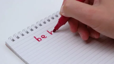 Man's hand writes the phrase be brave in red marker in a notebook. close up. 4k. Stock Footage 213985680