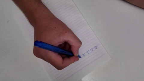 A mans hand writes text with a pen on a sheet of notebook paper. Stock Footage 318346857
