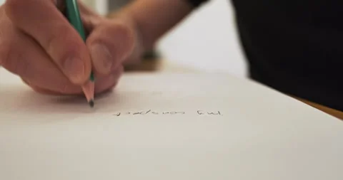 Man's hand writes text with a pencil on a sheet of paper. Close-up. Concept of 動画素材 263477221