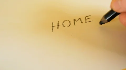 A man's hand writes the words Home with a black pencil on a white background Video stock 103368349