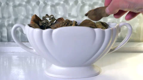 Man's hands adding potpourri pieces to a white decorative pot. Stock Footage 157849431