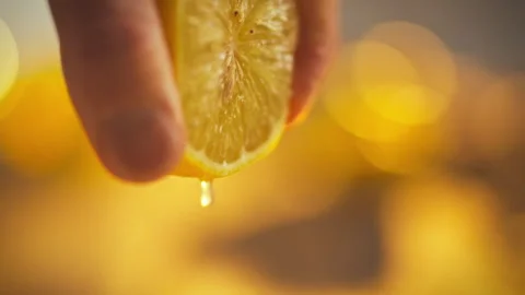 Mans hands apply gentle pressure to extract juice from fresh lemon on vibran Stock Footage 331355231