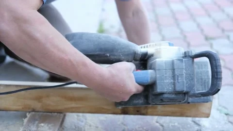 The man's hands are holding a grinding machine. Processing of a furniture part Stock Footage 204119925