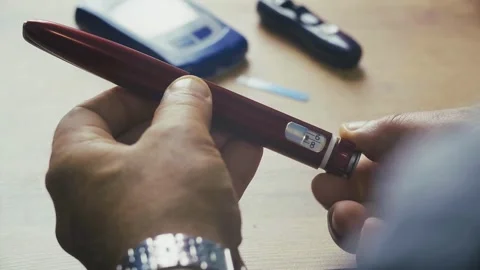 The man's hands are holding an insulin pen. Stock Footage 337704513
