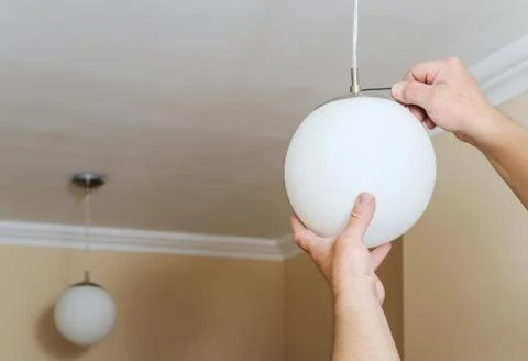 Man's hands are installing and connecting a lamp. Stock Photos