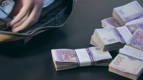 Man's hands are placing stacks of money into a bag Stock Footage 284445013