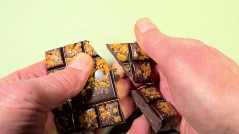 A man’s hands breaking off squares of chocolate and salted caramel pieces. Stock Footage 296275261