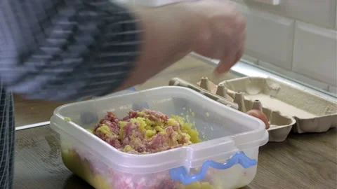 Mans hands breaks an egg into homemade minced meat, mixes with chopped potatoes Video stock 165069764