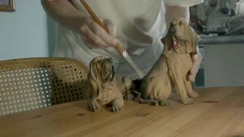 Mans hands brushing ceramic hound dogs. Color corrected version. Vidéo 72938610