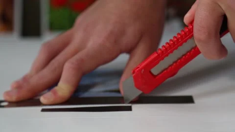The man's hands carefully cut out a small magnet with a knife. Stock Footage 148401151