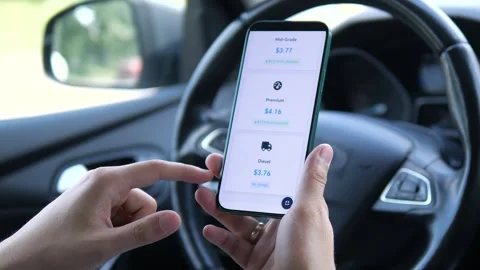 A mans hands check fluctuating fuel prices on a mobile application designed for Vídeo Stock 315210265