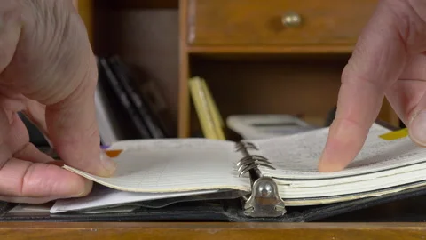 Man’s hands checking contact details in a personal organiser on a desk. Video stock 139068076
