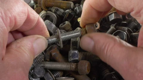 Man's hands choosing a nut, washer and bolt from an old pile. Video stock 159140971