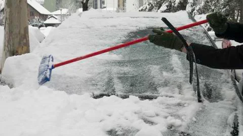Man's hands clearing snow of the front car window. Foto stock