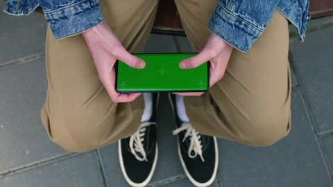 Man's hands click on the green screen of the phone, games on the phone Stock Footage 196118707