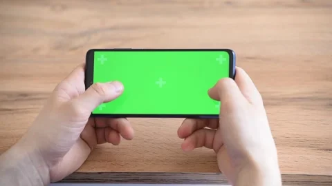 Man's hands click on the green screen of the phone, games on the phone Stock Footage 242405514