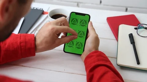 Man's Hands Close Up of Phone With Green Screen on White Office Wooden Table Stockbeeldmateriaal 109604510